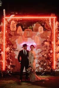 Bridal couple standing under neon arch