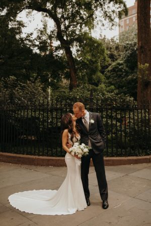 bride and groom kissing in city park
